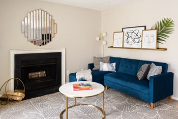 A blue couch with a white coffee table in front of a fireplace.